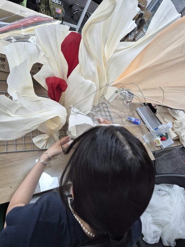 Overhead photograph of a Royal Blue studio work table showing student artworks in progress including dark figurative drawings and mixed-media pieces spread out alongside art tools
