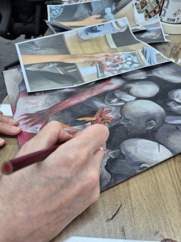 Close-up photograph of a student's hands carefully working with a colored pencil or pastel on a realistic rendering of stone or natural texture in a Royal Blue studio