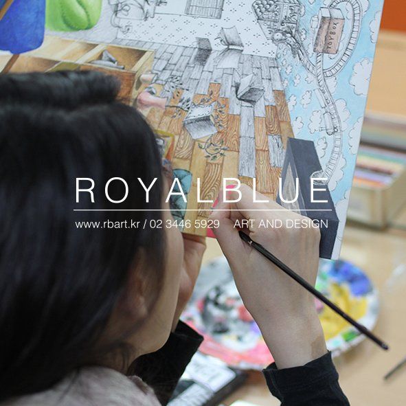 Royal Blue branded overhead close-up photograph showing a student working on a complex mixed-media artwork with layered sketches, magazine cutouts, and drawing elements spread across a surface