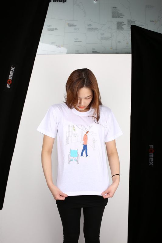 Photograph of a student modeling a t-shirt with a delicate illustration or print design in a studio or photography setting, displaying a fashion design or textile artwork