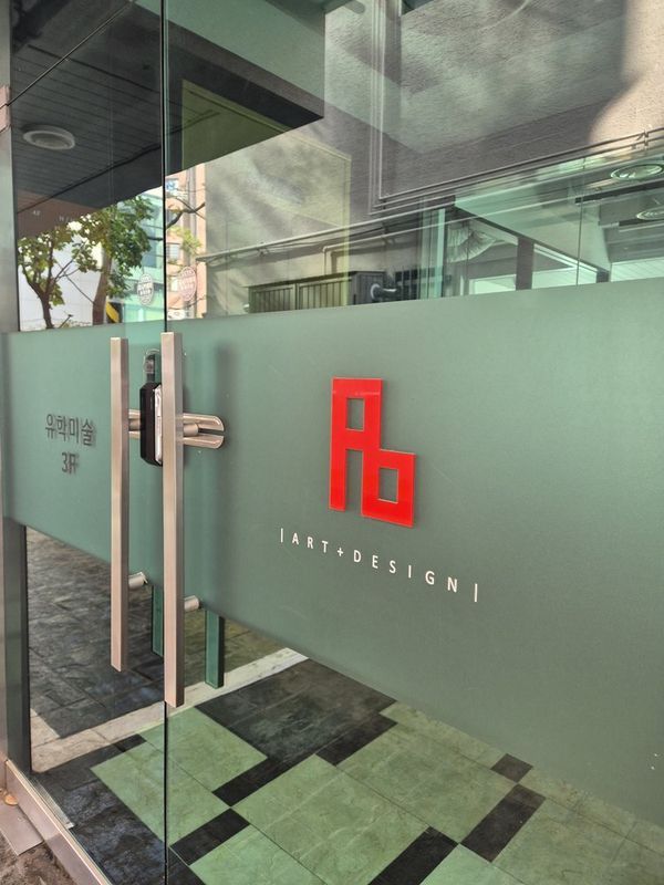 Close-up photograph of a frosted glass door with the Royal Blue Art and Design logo etched in red, showing the studio entrance with interior visible through the glass