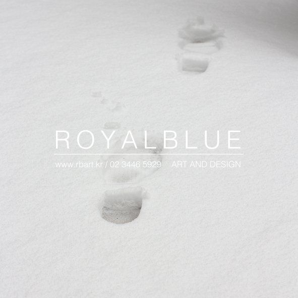 A Royal Blue branded promotional image showing a minimal white surface with small footprints or marks and soft shadows with the studio logo overlay on a clean white background