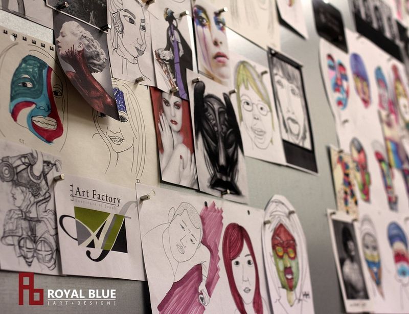 Interior photograph of a Royal Blue studio hallway display showing a dense arrangement of student portrait drawings, figure studies, and mixed-media works covering the full wall surface