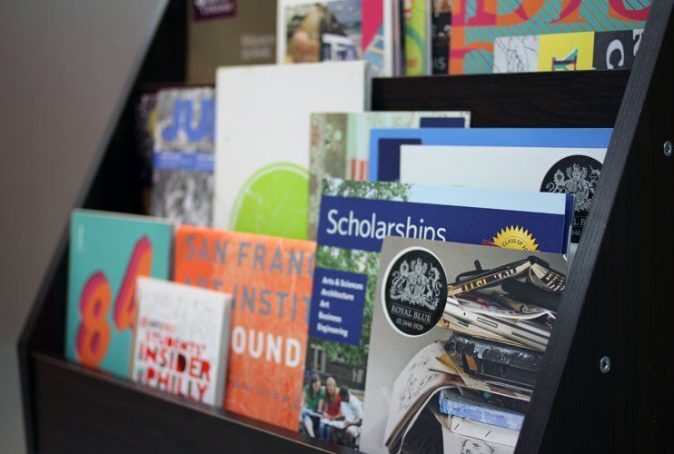 Interior photograph of a Royal Blue studio resource corner showing a rack or shelf filled with colorful books, magazines, and reference materials for student use