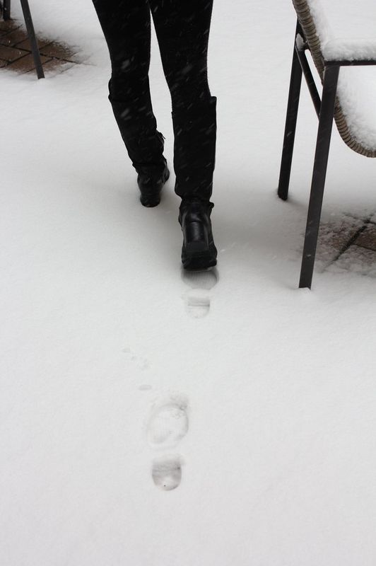 Interior photograph of a Royal Blue studio hallway or corridor showing a person in dark clothing walking past a bare white wall with minimalist table furniture