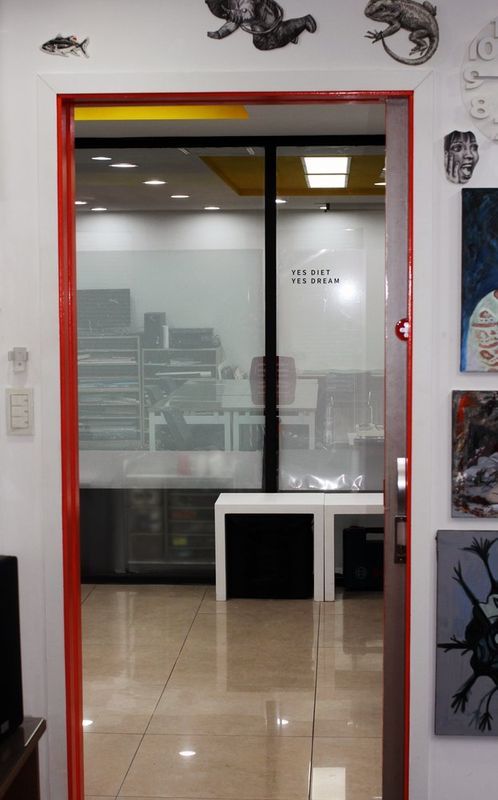 Interior photograph of a Royal Blue studio glass door entrance with the Rb logo visible on frosted glass panels, showing the bright modern interior of the facility beyond