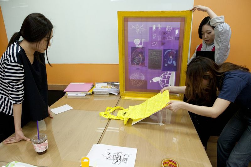 Photograph of a Royal Blue studio review session showing a student presenting or discussing a framed artwork with an instructor in a bright classroom setting